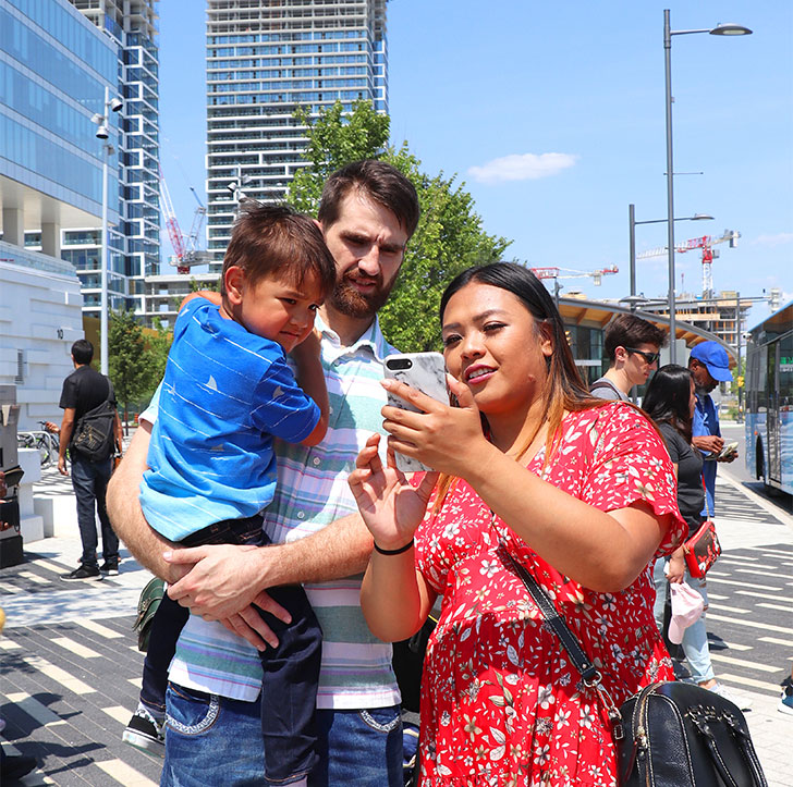A mother shows the diplay of her phone to her husband and young son.